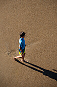 Kid on the beach under stone bridge Rocher du Basta, Biarritz, France