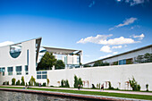 The German Chancellery stands prominently beside the Spree River, showcasing modern architecture and landscaped surroundings in Berlin.