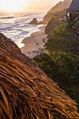 Young woman walking on the beach in front of Finca Barlovento at sunset, Tayrona National Park, Colombia