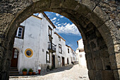 El arco de la muralla de Marvão en Portugal revela casas blancas y un cielo despejado en un día luminoso.