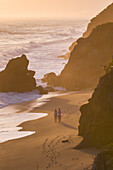 Couple walking on the beach in front of Finca Barlovento at sunset, Tayrona National Park, Colombia