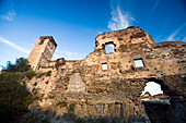 The remains of the Monjas Comendadoras convent showcase weathered stone walls against a bright blue sky in Alcántara, Extremadura.