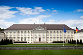 Schloss Bellevue, the German President\'s residence, stands majestically in Tiergarten, surrounded by manicured gardens under a bright sky.