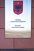 The sign of the Albanian embassy is prominently displayed on the wall in Berlin, showcasing its national emblem and details.