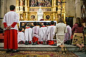 Altar boys kneel in prayer at Sagrario Church after a Corpus Christi procession in Seville, reflecting on the sacred moment in 2009.