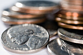 A close-up view of various US coins including a nickel featuring Jefferson, with pennies and dimes stacked nearby.