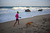 Kid walking his dog on the beach in front of Finca Barlovento, Tayrona National Park, Colombia