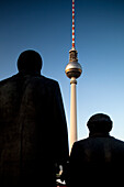 The statues of Karl Marx and Friedrich Engels stand prominently against the Berlin skyline, overlooking the Fernsehturm.