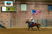 A cowgirl carrying the American flag gallops around the arena in the Grand Entry for the Moab Junior Rodeo in Utah.