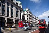 London, UK, May 2 2009, Two iconic red buses navigate bustling Regent Street under a bright blue sky in Westminster, London.