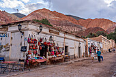 Tourists shop for souvenirs on street in front of the Hill of Seven Colors in Purmamarca, Argentina.