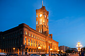 The Roten Rathaus stands majestically at dusk, showcasing its red facade and clock tower in Berlin, inviting visitors to explore.