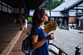 Young woman fanning herself at Tofukuji Temple in Kyoto, Japan