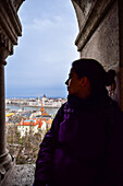 Young woman enjoying the view of Parliament building, Chain Bridge and Danube River through old columns, Budapest, Hungary, Europe