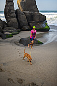 Kid walking his dog on the beach in front of Finca Barlovento, Tayrona National Park, Colombia