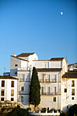 Discover the charming whitewashed homes perched by El Tajo gorge, with a serene sky above in Ronda, Andalusia.