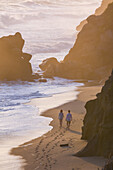 Couple walking on the beach in front of Finca Barlovento at sunset, Tayrona National Park, Colombia