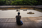 One man meditates at Japanese zen garden, Ryoan-Ji Temple in Kyoto