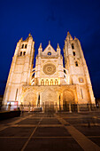 The majestic façade of León Cathedral is beautifully illuminated at night, showcasing intricate details against the dark sky.