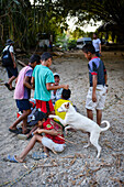 Eine Gruppe verspielter einheimischer Kinder hat Spaß mit einer Ausländerin, Santa Marta, Kolumbien