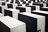 This memorial features numerous stark concrete slabs arranged in a grid pattern, symbolizing the memory of Holocaust victims.