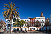 Carmona, Spain, Jan 8 2009, Visitors relax in San Fernando Square, surrounded by charming Mediterranean architecture and palm trees under a clear blue sky.