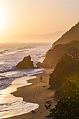 Couple walking on the beach in front of Finca Barlovento at sunset, Tayrona National Park, Colombia