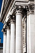 The elegant neoclassical columns of Trinity College showcase intricate details against a clear blue sky in Dublin.