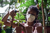 Young afro latin woman gardening wearing a face mask