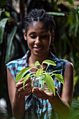 Young afro latin woman gardening and holding an hydroponic plant