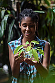 Young afro latin woman gardening and holding an hydroponic plant