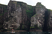 Paddler auf einem Standup Paddle Board (SUP) vor der Nordwestküste Schottlands und den Klippen von Handa Island, Sutherland, Highlands, Schottland, Vereinigtes Königreich, Europa