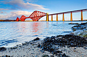 Leuchtend roter Bahnübergang Forth Bridge, UNESCO-Weltkulturerbe, am FA?rth of Forth in South Queensferry, nahe Edinburgh, Schottland, Vereinigtes Königreich, Europa