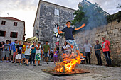 Young boys jumping over a wood fire beside the Cathedral St. Marka, Korcula old town, Korcula island, Croatia, Southeast Europe