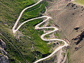 Aerial view of a winding mountain road curves, Kalmak Ashuu Pass, through lush greenery in Kyrgyzstan, Central Asia, Asia