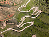 Aerial view of a winding mountain road curves, Kalmak Ashuu Pass, through lush greenery in Kyrgyzstan, Central Asia, Asia