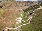 Aerial view of a winding mountain road curves, Kalmak Ashuu Pass, through lush greenery in Kyrgyzstan, Central Asia, Asia