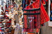 Close-up of colorful handbags with text saying Cusco (Cuzco), Pisac market, Pisac, Sacred Valley, Urubamba Province, Cusco (Cuzco) Region, Peru, South America