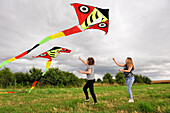 Two teenage girls flying a kite, Centre-Val de Loire region, France, Europe