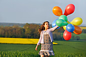 Little girl playing with balloons in the fields, Eure-et-Loir department, Centre region, France, Europe