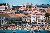 Visitors enjoy a sunny day on the beach in Cascais, surrounded by colorful umbrellas and historic buildings, Portuguese Riviera, Cascais, 30km west of Lisbon, Portugal, Europe