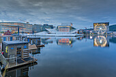 View of saunas, Oslo Opera House and Munch Museum reflecting in harbour on cloudy evening, Oslo, Norway, Scandinavia, Europe