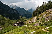 Steinhütte in einem alpinen Wald auf einem Wanderweg im Alagna Valsesia-Gebiet in den italienischen Alpen, Piemont, Italien, Europa