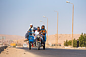 Family travelling on a motorized tricycle to a village on the Nile near the Necropolis of El-Kab, on the eastern bank of the Nile, Egypt, North Africa, Africa