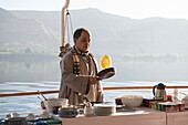 Cook preparing breakfast pancakes on the upper deck of the dahabeah, passenger river boat of the Lazuli fleet, sailing on the Nile river, Egypt, North Africa, Africa