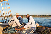 Members of the crew sitting at the prow of a dahabeah, passenger river boat of the Lazuli fleet, sailing on the Nile river, Egypt, North Africa, Africa