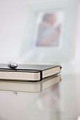 Close up of a black notebook and pen resting on a glass desk