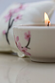 Close up of a burning pink tea light and matching cushion