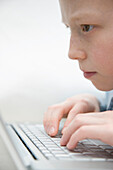 Extreme close up of a boy typing on laptop computer keyboard