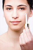 Close up of a young woman applying an anti-aging serum on her face with a dropper